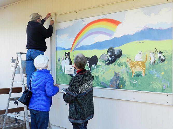 Volunteer Dave Holtz mounting a memorial tile on the wall beside the Rainbow Bridge mural